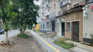 Una calle residencial con edificios de varios pisos, una acera y un árbol.