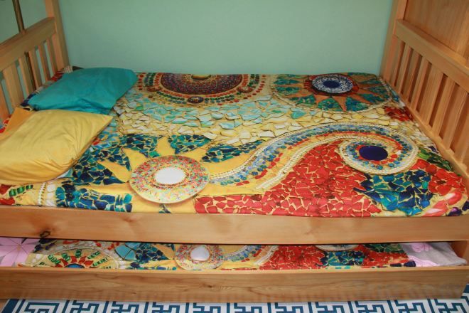 Una cama con un edredón colorido y estampado, y dos almohadas.