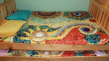 Una cama con un edredón colorido y estampado, y dos almohadas.