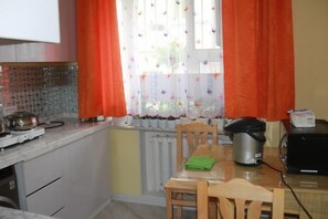 A kitchen with a window, a table, chairs, a kettle, a toaster, and a radiator. - Happy Hostel (Ulaanbaatar)
