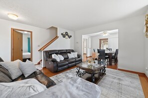 A modern living room with a leather sofa, a glass coffee table, and a dining area with a wooden table and chairs. - 3BR Cozy&Peaceful Retreat +small gym (Cleveland)