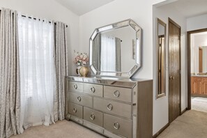 Une chambre à coucher avec une commode, un miroir et une porte donnant sur une autre pièce.
