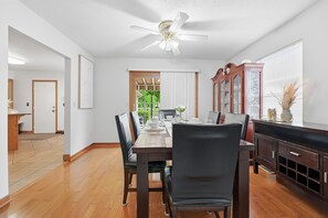 Un espace repas comprenant une table en bois, des chaises et un ventilateur de plafond.