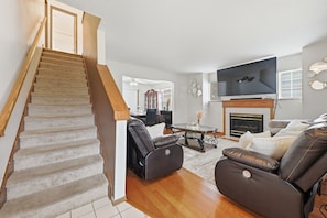 A staircase leading to a living room with a fireplace, leather sofas, and a flat-screen TV. - 3BR Cozy&Peaceful Retreat +small gym (Cleveland)