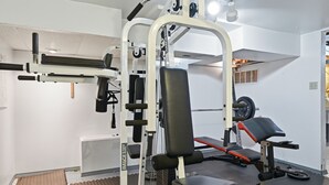 Une salle de sport équipée de divers appareils d’exercice, notamment un banc de développé couché, des supports à poids et un rack à squats.