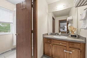 Une salle de bain avec un meuble-lavabo en bois, un évier, un miroir et un porte-serviettes.