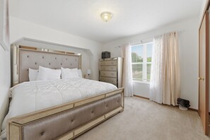 Une chambre à coucher avec un lit, une commode et une fenêtre avec des rideaux.
