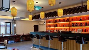 A bar area with a counter, bar stools, and a wall of bottles. - TDH HOTEL (Ikeja)