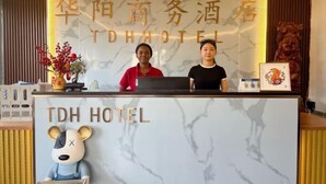 A hotel reception desk with a marble top and a bear mascot. The hotel name is displayed in both English and Chinese. - TDH HOTEL (Ikeja)