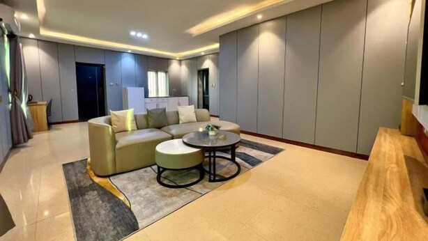 A modern living room with a sectional sofa, two round coffee tables, and a wooden bench. - TDH HOTEL (Ikeja)