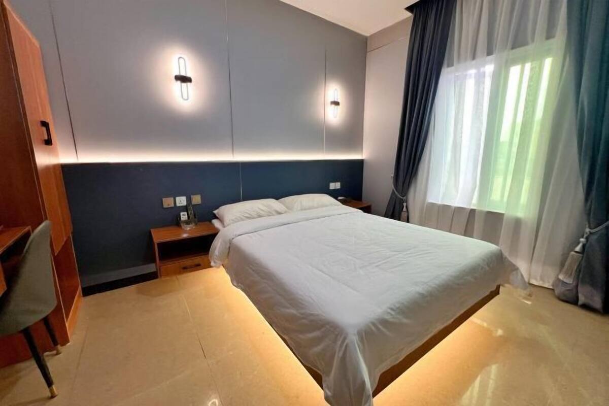 A bedroom with a bed, bedside tables, a desk, and a chair.