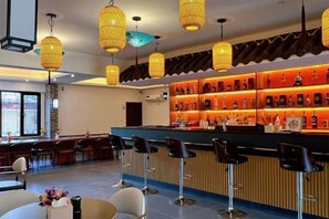 A bar area with a counter, bar stools, and shelves of bottles. - TDH HOTEL (Ikeja)