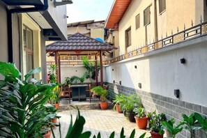 A covered outdoor seating area with potted plants and a pergola. - TDH HOTEL (Ikeja)
