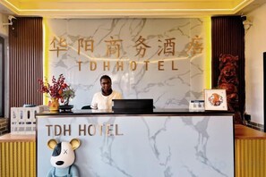 Un comptoir d’accueil d’hôtel avec un plateau en marbre et une enseigne indiquant « HÔTEL TDH ».