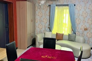 A room with a bed, a sofa, a dining table, and a wardrobe. - TDH HOTEL (Ikeja)