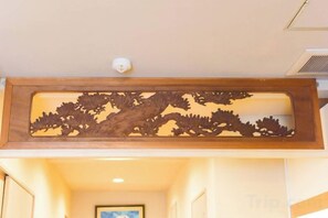 Un couloir avec un panneau décoratif en bois au-dessus d’une porte.