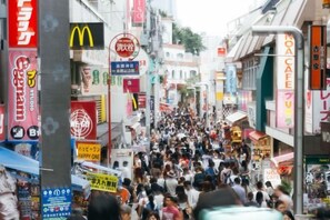 A crowded urban street with various commercial signs and storefronts. - Yoyogi Shinjuk House (Tokyo)