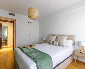 A neatly arranged bedroom with a bed, bedside tables, and a hanging light fixture.