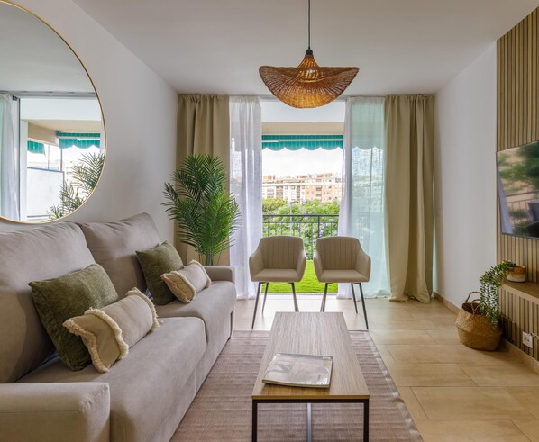 A modern living room with a sofa, two armchairs, a coffee table, and a television.