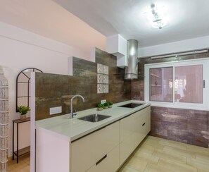 A modern kitchen with a large island, stainless steel appliances, and a view to the outside.