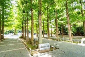 A pathway lined with trees, a signpost, and a railing. - Ikebukuro Central Hotel (Tokyo)