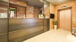 A reception area with a brick wall, a glass partition, and an elevator. - ZAZA Hotel (Bucheon-si)
