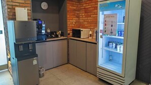 A kitchenette with a coffee machine, a refrigerator, and a drink vending machine. - ZAZA Hotel (Bucheon-si)