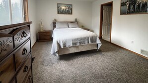Un dormitorio con cama, cómoda, mesita de noche y dos cuadros en las paredes.