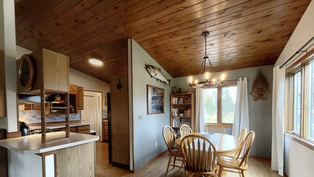 Una cocina con armarios de madera, una isla central y un comedor con sillas de madera y una araña.