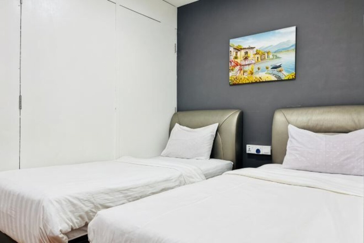 Una habitación con dos camas, una pared gris y un cuadro.