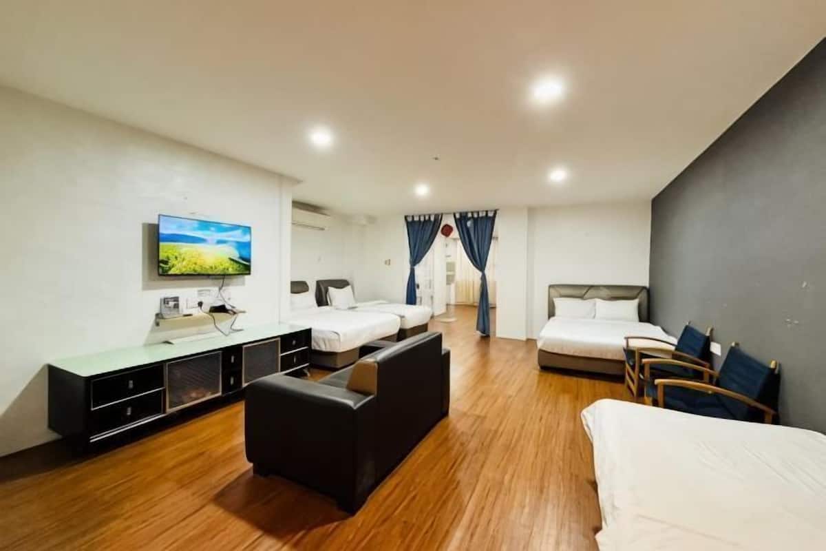 A hotel room with a bed, a sofa, a TV, a desk, and a window.