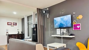 A modern living room with a sofa, a TV, a fan, a kitchen area, and a dining table. - Hotel Traveler's Majestic Retreat, Located in the Heart of Melaka (Melaka)