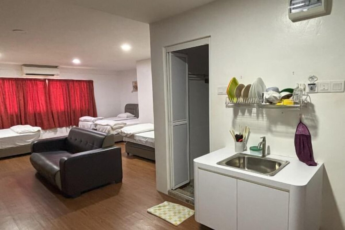 A compact hotel room with a kitchenette, a seating area, and a bed.