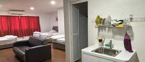 A compact hotel room with a kitchenette, a seating area, and a bed.
