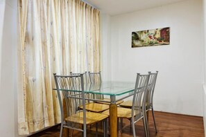 A dining area with a glass table and metal chairs, a wooden floor, a white wall, and a painting. - Hotel Traveler's Majestic Retreat, Located in the Heart of Melaka (Melaka)