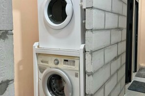 A stacked washer and dryer unit against a wall with a brick pattern. - Tonbon Home - Japanese style living (Ho Chi Minh City)