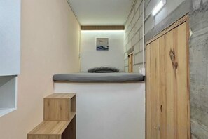 A compact room with a built-in bed, wooden wardrobe, and a small shelf unit. - Tonbon Home - Japanese style living (Ho Chi Minh City)