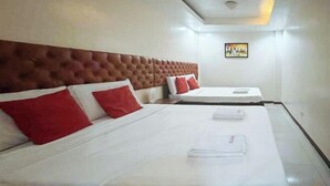 Ein Hotelzimmer mit zwei Betten, jeweils mit weißer Bettwäsche und roten Kissen.