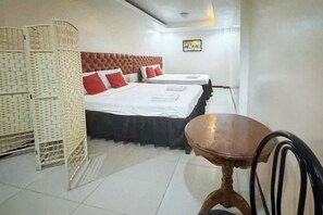 A hotel room with two beds, a wooden table, and a woven partition. - Pensionne Alonso by RedDoorz (General Santos)