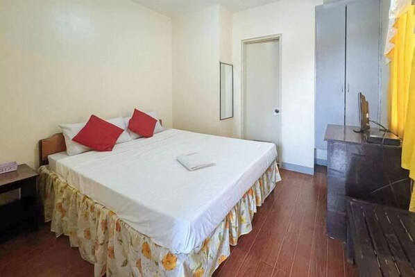 A bedroom with a bed, a nightstand, a wardrobe, and a desk with a chair.