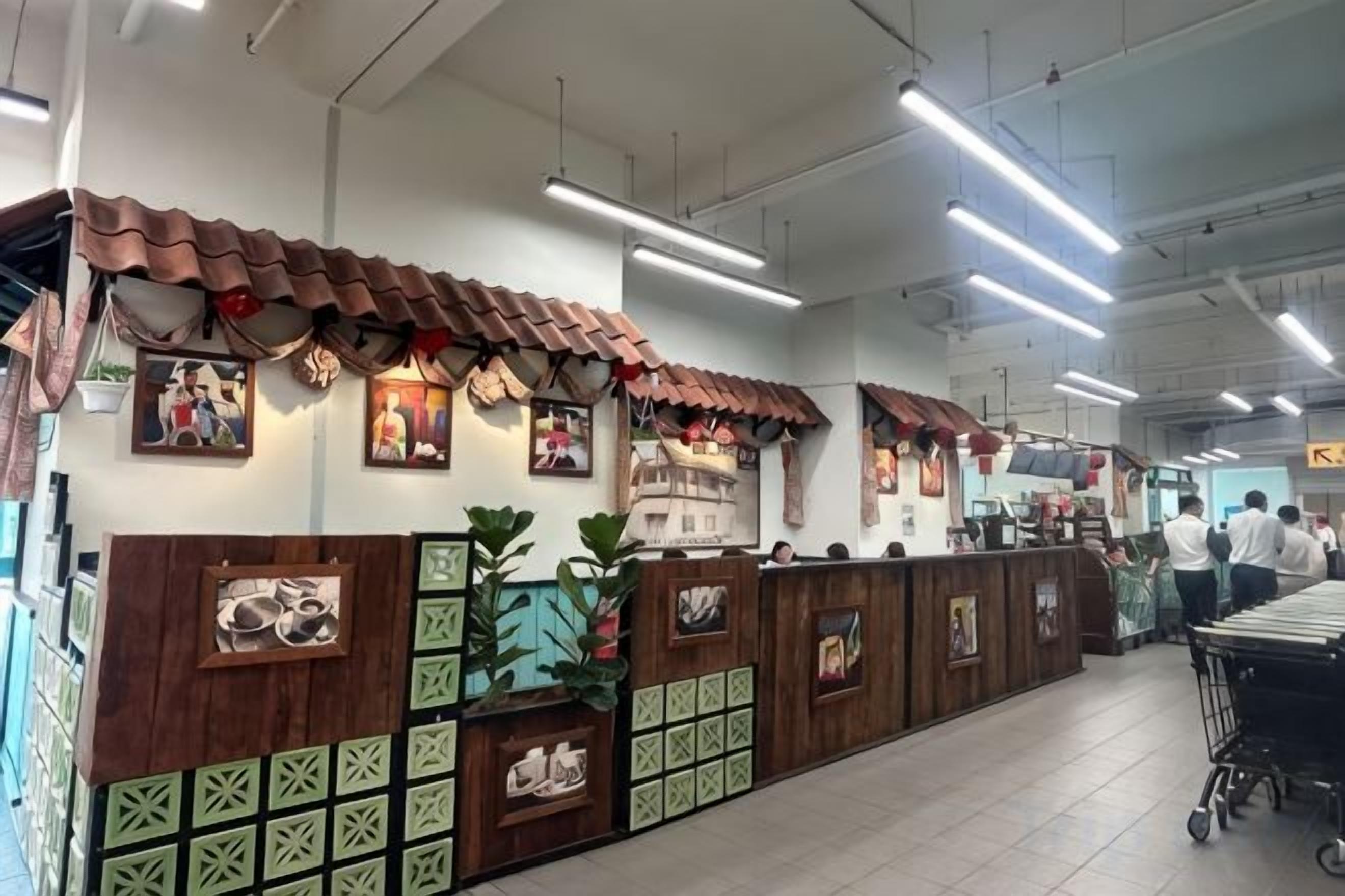 A restaurant interior with a long counter, tiled ceiling, and wall-mounted pictures.