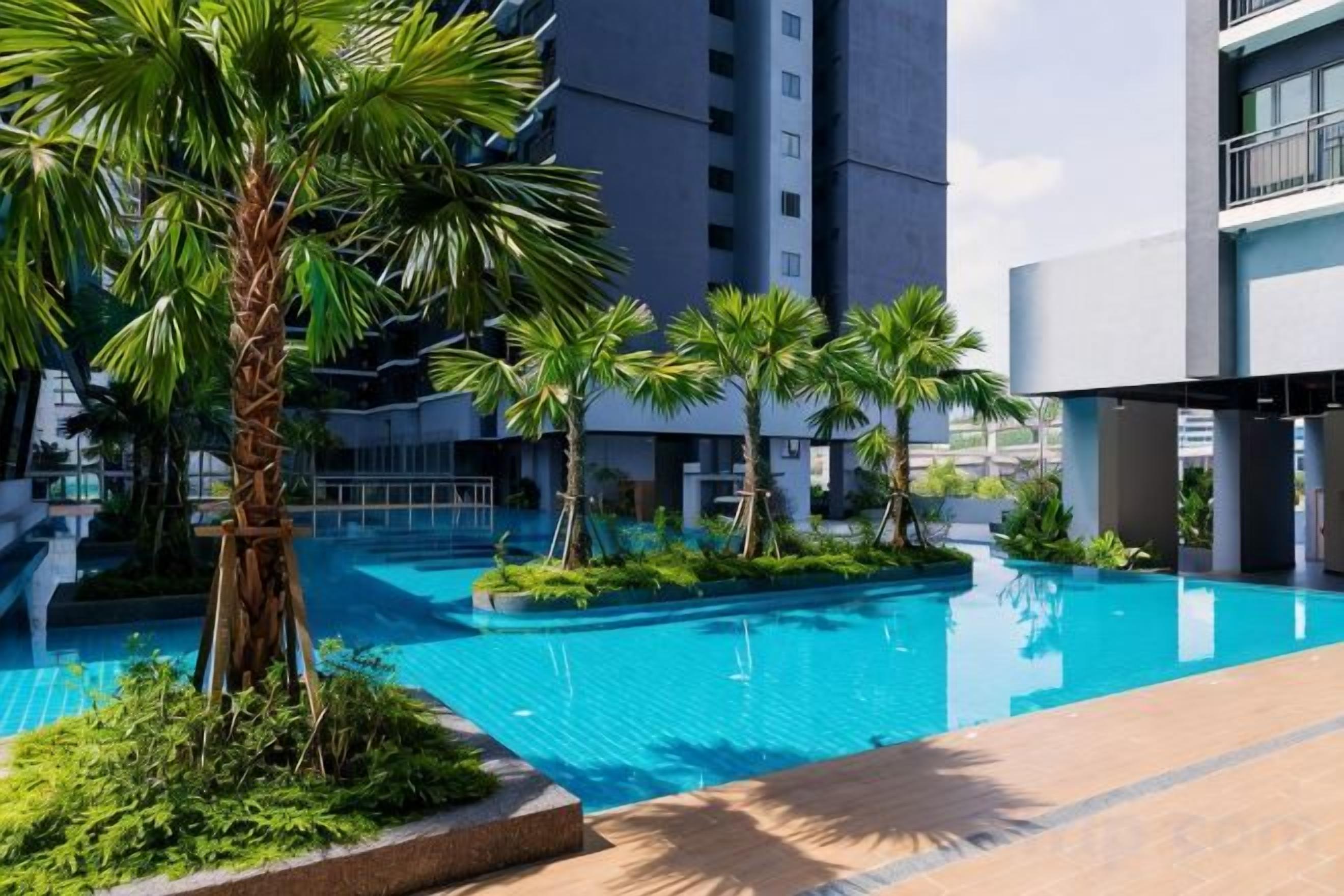 A swimming pool surrounded by palm trees and modern buildings.