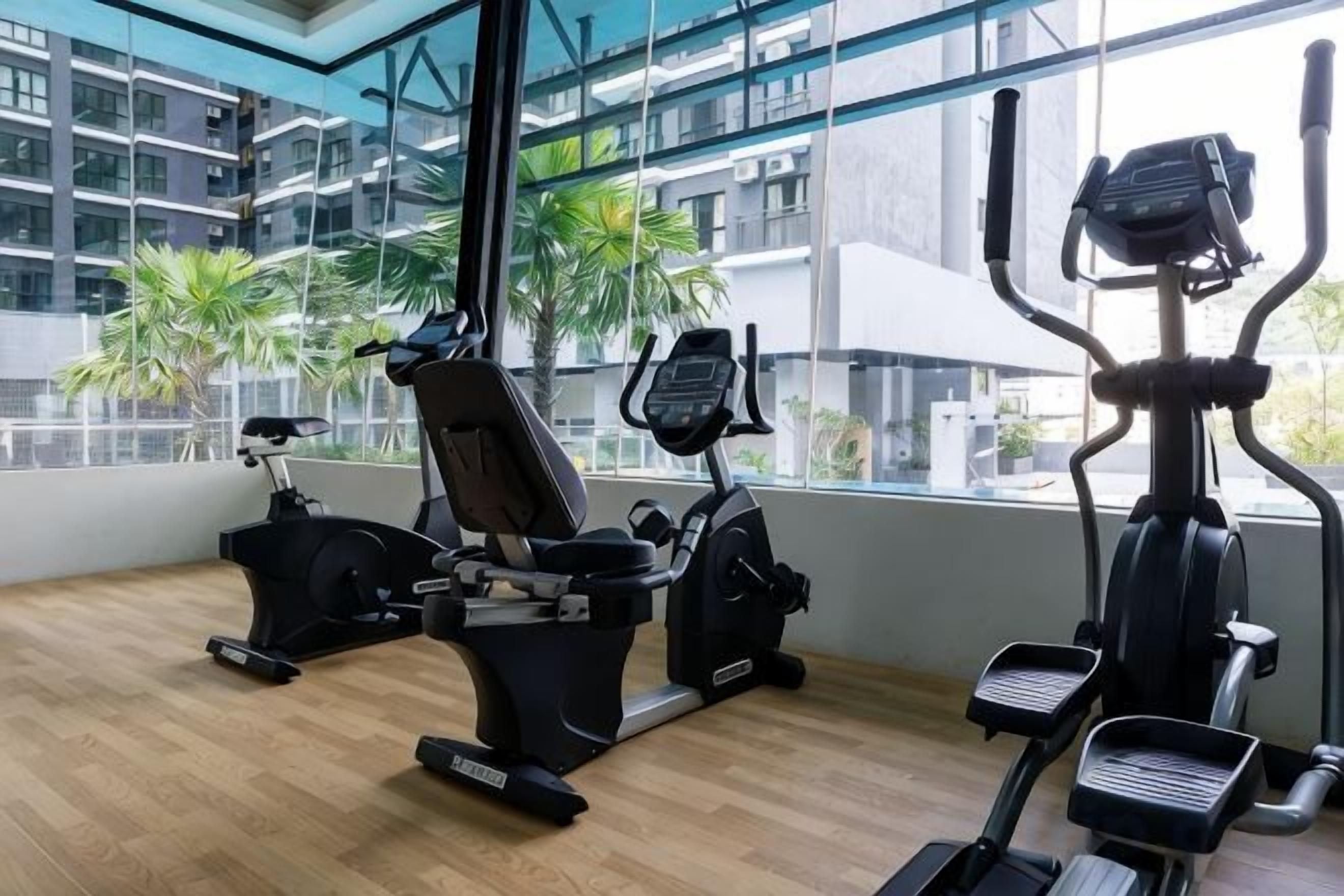 Ein Fitnessstudio mit Cardiogeräten und Blick aus dem Fenster auf ein Gebäude.