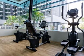 A gym with cardio machines and a window view of a building. - MAXIM BY FEEL HOME (Kuala Lumpur)