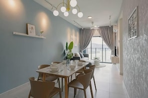 A dining area with a table set for six, a sofa, and a large window with curtains. - MAXIM BY FEEL HOME (Kuala Lumpur)