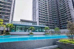 Ein Hochhaus mit Wohnungen, einem Schwimmbad, moderner Architektur und umliegender Grünfläche.
