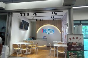 A restaurant interior with a neon sign, tables, chairs, and a menu board. - MAXIM BY FEEL HOME (Kuala Lumpur)
