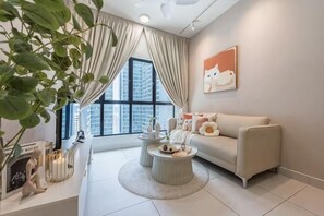 A modern living room with a sofa, coffee table, and a large window with curtains. - MAXIM BY FEEL HOME (Kuala Lumpur)