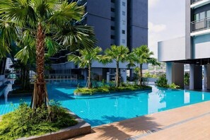 A swimming pool surrounded by palm trees and modern buildings. - MAXIM BY FEEL HOME (Kuala Lumpur)