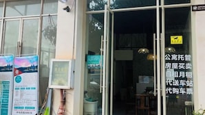 A hotel entrance with glass doors, a signboard with text, and a small window with a view. - Boten YouJia Residential Hotel (Nateuy)